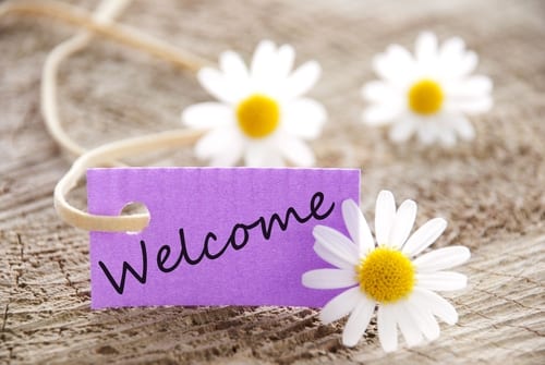 Welcome written on a tag with daisies around it